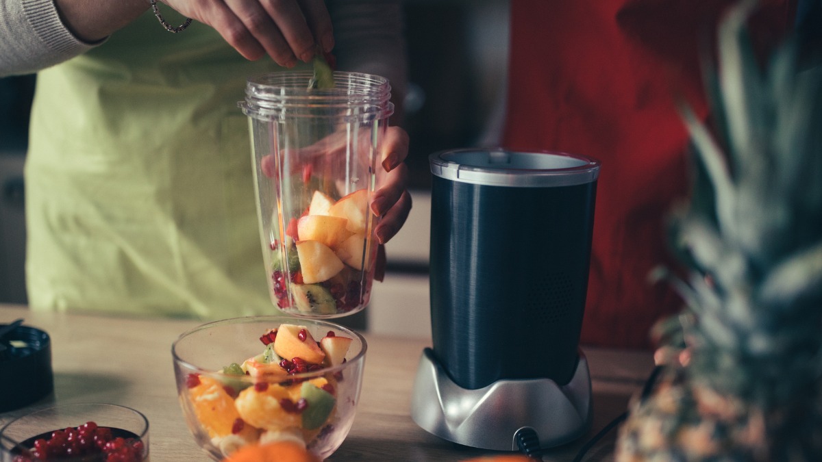 vrouw maakt smoothie met fruit in nutribullet blender